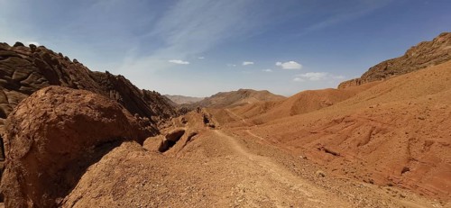 Desert hills with eroded rocks and trails under clear skies, Morocco