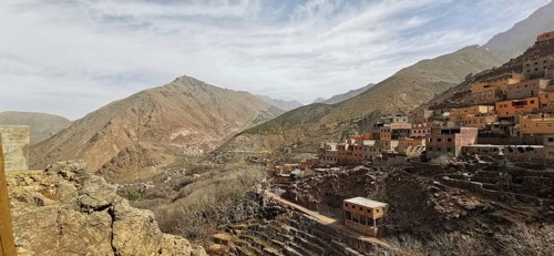 A rocky valley with a village in the mountains under cloudy sky, Atlas Mountains, Morocco