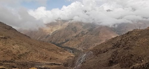 A barren mountain landscape under a cloudy sky with visible trails, Atlas Mountains, Morocco