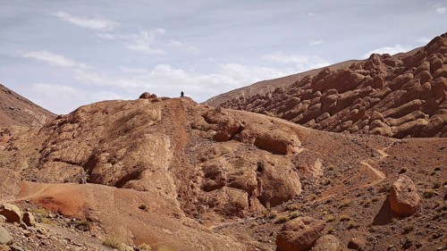 Rocky hills with a person on the summit under a cloudy sky, Morocco