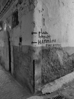 Dilapidated wall with graffiti and references to a hammam in a narrow alley, monochrome, old town