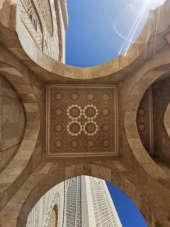 View from below of an ornate stone dome with geometric patterns and blue sky in the background