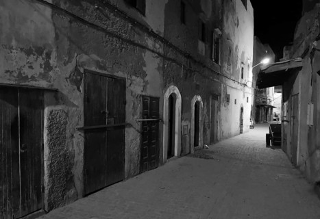 Nocturnal alley with old facades and closed door in a quiet area, monochrome, old town of