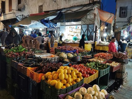 Bustling night market in the Medina with colorful stalls full of fruit and vegetables, people