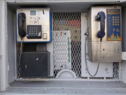 Two retro-designed telephone booths in an urban setting with metal grille and shades of gray,