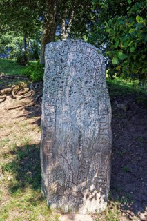 Runestone with carved runes symbols standing on forest ground by a forest, Hornborgasjön, Sweden