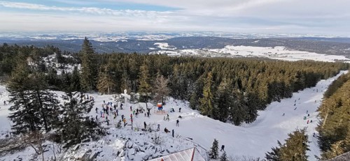 Winter landscape with snow-covered forest and people skiing, ski lift at Ochsenkopf, Fichtelgebirge