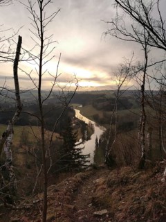 A river snakes through a hilly landscape at sunset, looking across the Saxon Saale from the