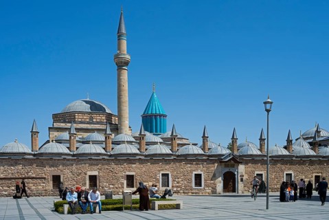 View of a large mosque with minaret and domes surrounded by people and blue sky, Mevlana Museum,