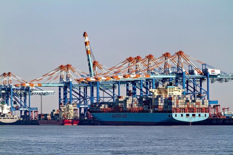 Large cargo ship loaded with containers surrounded by blue port cranes, The cranes of the Bremen