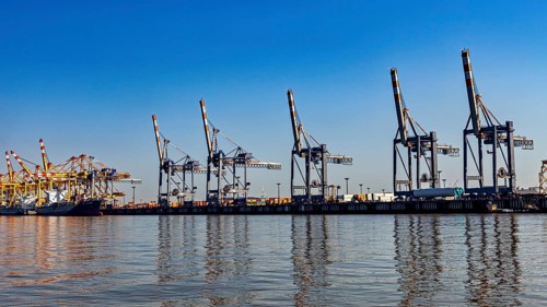 Cranes at the harbor in clear blue sky, reflected in the water, industrial ambiance, The cranes of