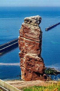Isolated rock by the sea with a harbor wall in the background, the high-seas island of Heligoland
