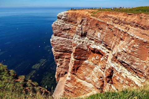Rocky cliffs tower over the calm blue sea, the high-seas island of Heligoland in the North Sea