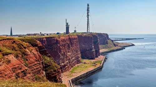 Red cliffs with lighthouse under blue sky on the coast, the high-seas island of Heligoland in the