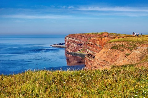 Grassy cliffs with calm seas under clear skies, The high-seas island of Heligoland in the North Sea