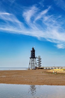 A lighthouse on the beach under a clear sky with picturesque clouds, Die Kugelbake von Cuxhaven