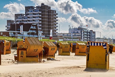 Yellow beach chairs on the beach in front of skyscrapers and a cloudy summer backdrop, beach chairs