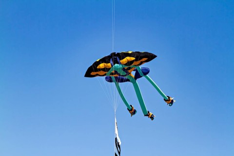 A colorful kite flies high in the blue sky under clear weather conditions, a kite in the air