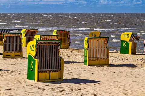There are some beach chairs on a bright beach with a sea background under a blue sky, beach chairs