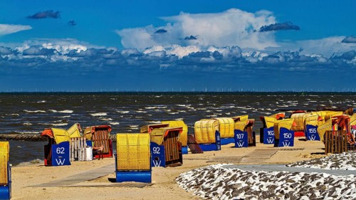 Several beach chairs along a windy beach with dramatic sky in the background, beach chairs on