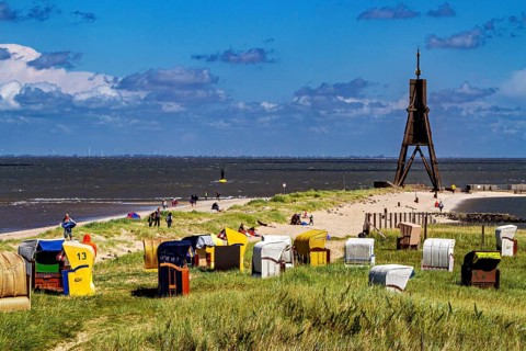 Beach on the North Sea coast with lighthouse and beach chairs under a blue sky, beach chairs on the