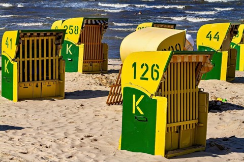 Yellow and green beach chairs stand in the sun on the beach with a view of the sea, beach chairs on