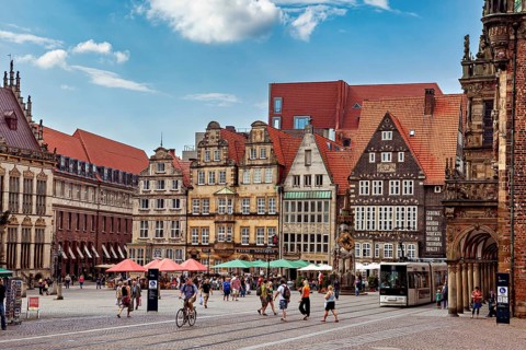 Lively historic old town with half-timbered houses and a tram against a clear blue sky, the center