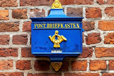 A blue yellow mailbox on a brick wall, nostalgic design, historic blue mailbox