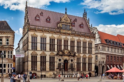 Magnificent Renaissance building with ornate details surrounded by people on a sunny square, The