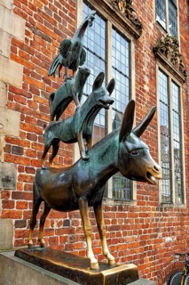 Bronze sculpture of the Town Musicians in front of a brick wall with windows, The Bremen Town