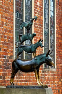 Bronze sculpture of the Bremen Town Musicians in front of a historic brick wall, The Bremen Town