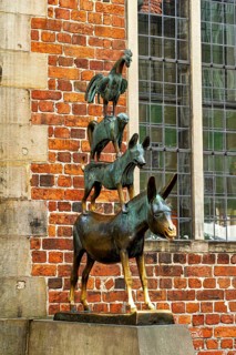 The Town Musicians of Bremen as a bronze sculpture in front of an old wall with windows, The Bremen