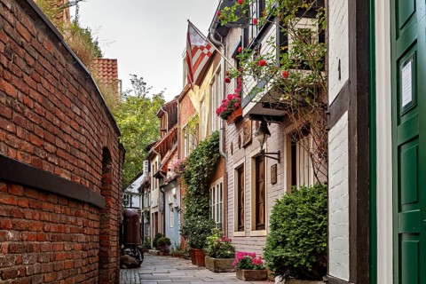 Narrow old town alleyway next to a brick wall, lined with charming houses and an idyllic