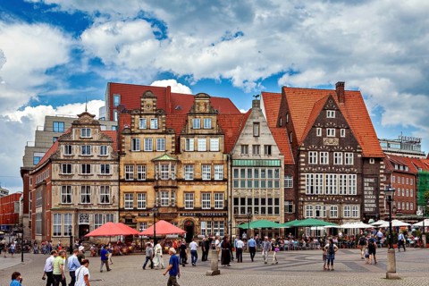 Historic old town with half-timbered houses and people on a busy market square under a blue sky,