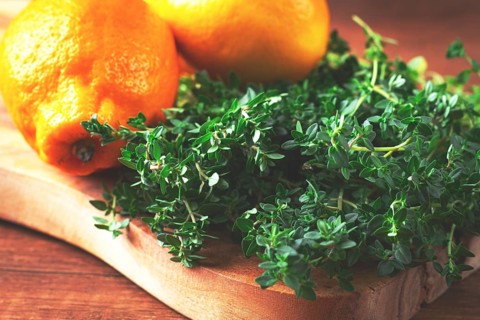 Lemon thyme, on a wooden chopping board, with lemons, close-up