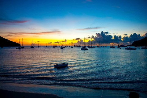 Romantic evening mood over Tyrrell Bay with many sailboats sailing yachts, moored rowing boat on