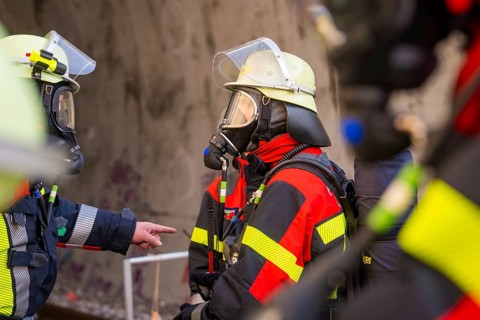 Firefighters talking, equipped with respiratory protection and protective equipment, in a tunnel,