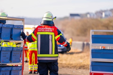 A firefighter in uniformed clothing stands on a railway line with equipment, fire department