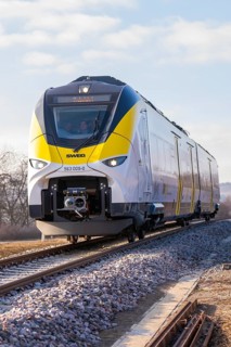 Modern railway runs on rails through rural areas under blue skies, fire brigade exercise at the