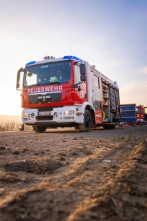 A fire truck stands on a country road in patrol light, firefighters ready to act, fire brigade