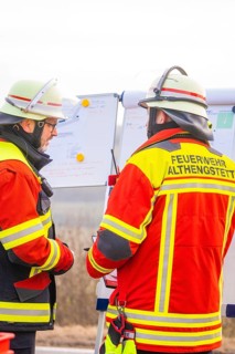 Firefighters at an outdoor briefing, analyzing plans and coordinating strategies, fire brigade