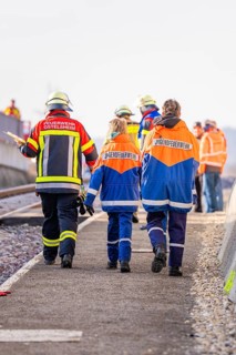 People wearing fire uniforms walk along a railway line, fire brigade exercise at the Hermann Hesse
