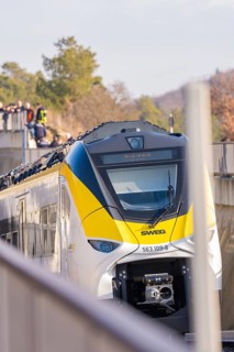 A train runs along the edge at an elevated point with spectators, fire department exercise at the