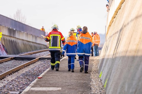 Firefighters in uniforms walk along railroad tracks, sunny background, fire brigade exercise on the