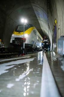 A train in a tunnel surrounded by firefighters on wet ground during rescue work, fire brigade