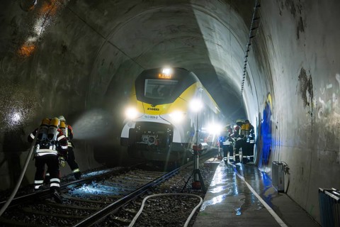 Firefighters during an emergency operation in a dark train tunnel next to a stationary train, fire