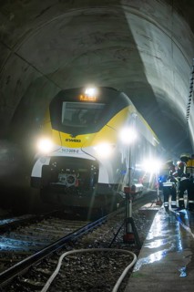 Train crosses an impressively illuminated tunnel with firefighters, fire brigade exercise on the