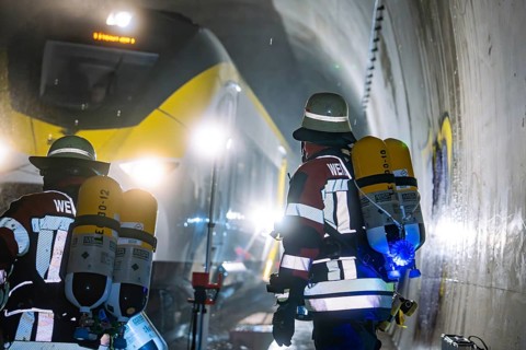 Firefighters wearing respiratory protection against a yellow train in a tunnel, fire brigade