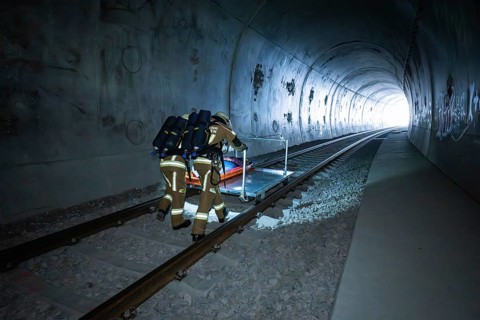 Two firefighters push a stretcher through a dark tunnel, fire brigade exercise on the Hermann Hesse