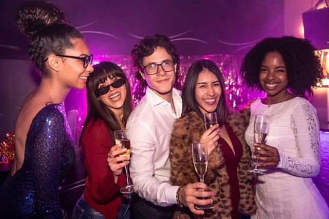 Diverse group of smiling friends celebrating together during a festive event, holding champagne